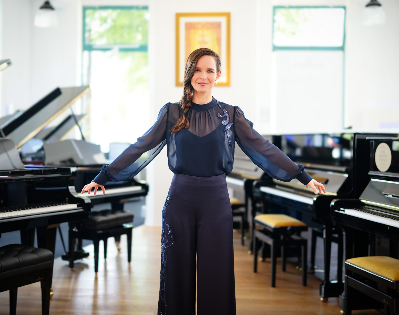 Pianistin in einem asymmetrischen dunkelblauen Konzertensemble von Marillon Couture, stehend